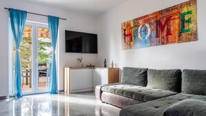 Un salon moderne avec un canapé, un téléviseur à écran plat et un tableau accroché au mur.