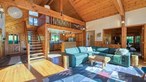 A spacious living area with a wooden ceiling, a sofa set, a coffee table, and a staircase leading to an upper level. - Private Lake Cabin Near Yosemite with a Hot Tub (Midpines)