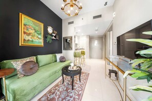 A modern living room with a green sofa, a coffee table, and a dining area with chairs. - Stayshort - 1 Bed in Zada Tower Sleeps 3 With Balcony (Dubai)