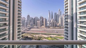Um edifício alto com várias varandas e vista para um horizonte urbano com diversos arranha-céus.