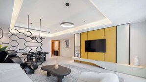 Uma sala de estar moderna com sofá, mesa de centro e TV fixada em uma parede amarela.