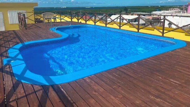 Ein Schwimmbecken auf einer Holzterrasse mit Blick auf die Landschaft.
