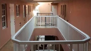 Ein mehrgeschossiges Interieur mit einem offenen zentralen Bereich, Geländern und einer Deckenleuchte.