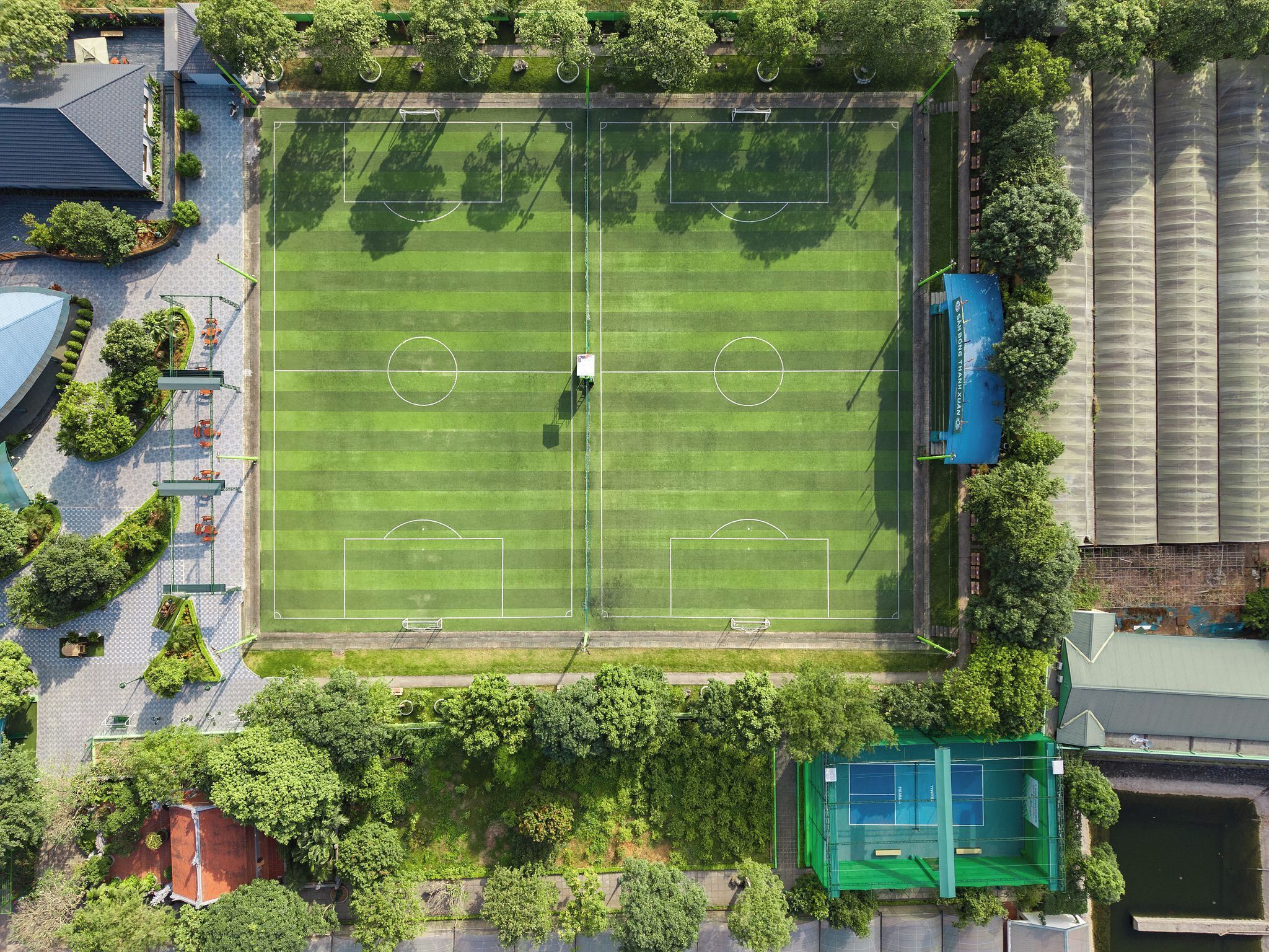 An aerial view of a soccer field surrounded by trees and buildings.