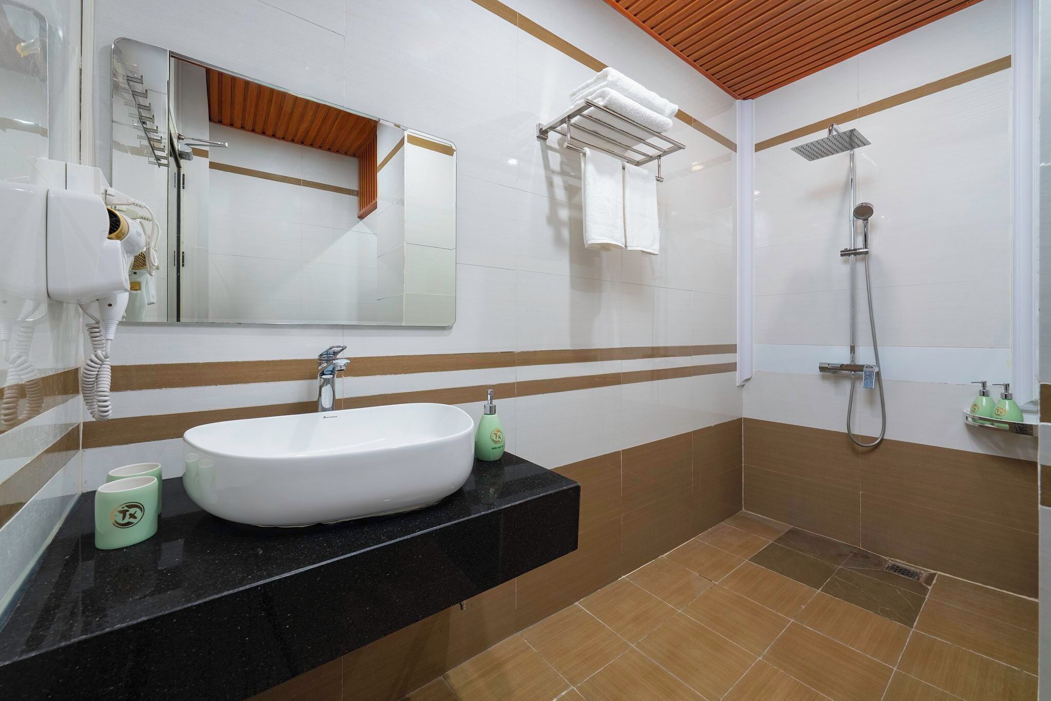 A modern bathroom with a white sink, a mirror, a shower, and a towel rack.