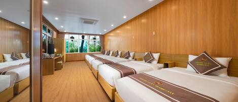 A hotel room with multiple beds, wooden paneling, and a view of greenery outside.