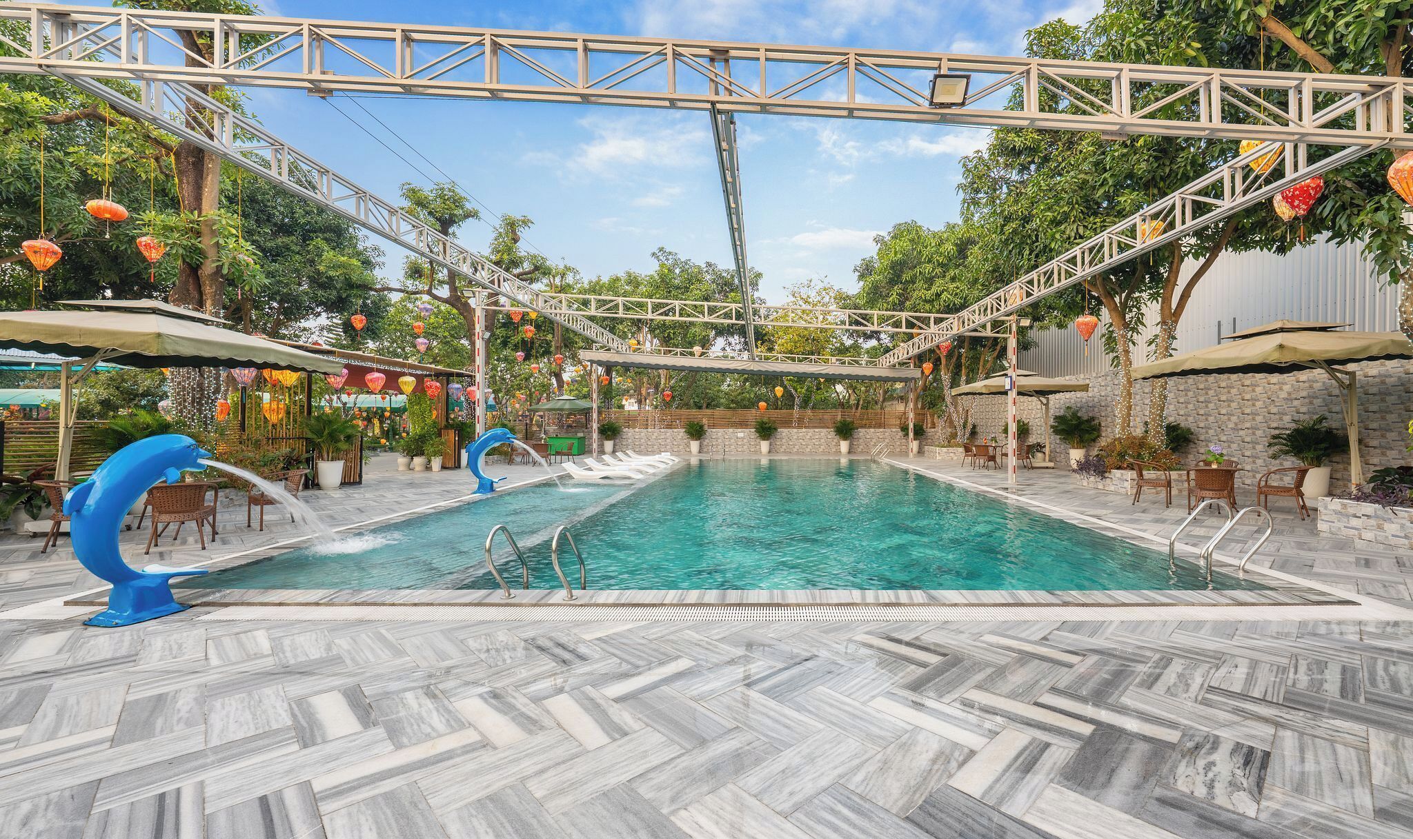 A swimming pool with a blue dolphin sculpture, surrounded by outdoor seating and potted plants.