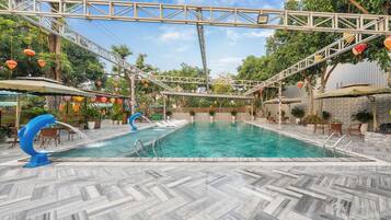 A swimming pool with a blue dolphin sculpture, surrounded by outdoor seating and potted plants.