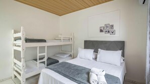 A bedroom with bunk beds, a bed with a grey headboard, and a wall with framed pictures. - Complete House Just Minutes From the Beach Jcs0874 (Penha)