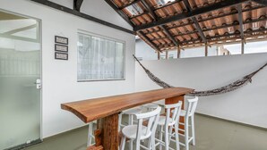 A modern interior with a wooden table and white chairs, a hammock, and a glass door. - Complete House Just Minutes From the Beach Jcs0874 (Penha)