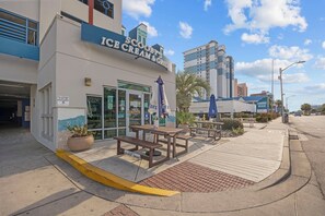 Un edificio con un cartello che indica 'Scooby's Ice Cream & Grill' e un cartello con scritto 'Pizza'. Sono presenti tavoli all'aperto e un cartello con la scritta 'Solo Ospiti'.