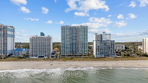 Ein Strandhotel mit mehreren Hochhäusern, einem Sandstrand und Wellen.
