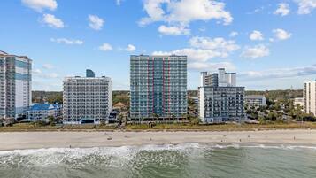 A beachfront hotel with multiple high-rise buildings, a sandy beach, and ocean waves.