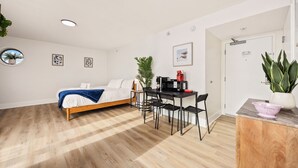 Ein modernes, kompaktes Zimmer mit einem Bett, einem kleinen Esstisch mit Stühlen, einer Mikrowelle und einem Spülbecken.