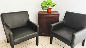 Two black leather armchairs and a small wooden table with a potted plant. - Mexican Cozy Apartment (Puerto Vallarta)