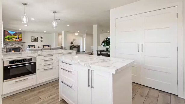 Een moderne keuken met witte kasten, een marmeren eiland en geïntegreerde apparaten.