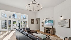 Ein geräumiges Wohnzimmer mit einer großen Ledersofa, einem Chandelier und einem Fernseher.