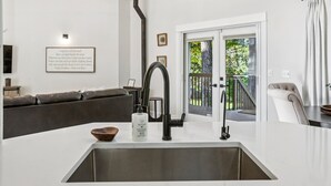Eine moderne Küche mit einer großen Kochinsel, einem schwarzen Wasserhahn und einer Pendelleuchte.
