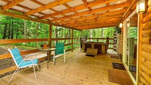 A wooden deck with a table and chairs, a barbecue grill, and a glass door leading to a forested area. - Pine View Cabin at Hocking Hills (South Bloomingville)