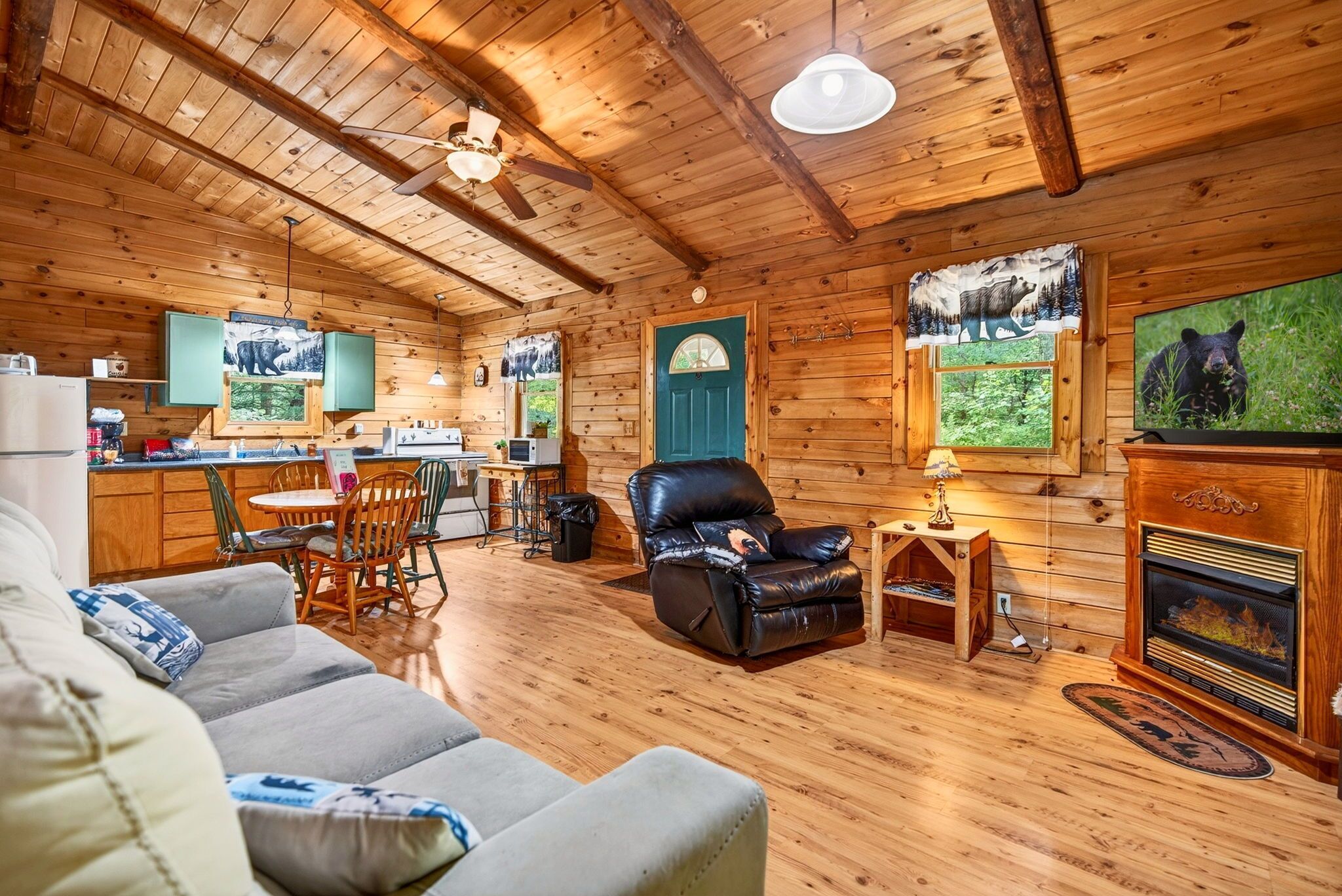 L’intérieur d’une cabane en rondins, avec une cheminée, un fauteuil inclinable en cuir, un coin repas et des murs en bois.