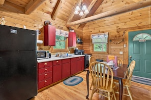 Ein Holzblockhaus-Interieur mit einer Küche, einem Essbereich und einer grünen Tür.
