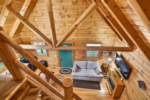 Ein Holzblockhaus-Innenraum mit einer Couch, einem Fernseher und einer Treppe.