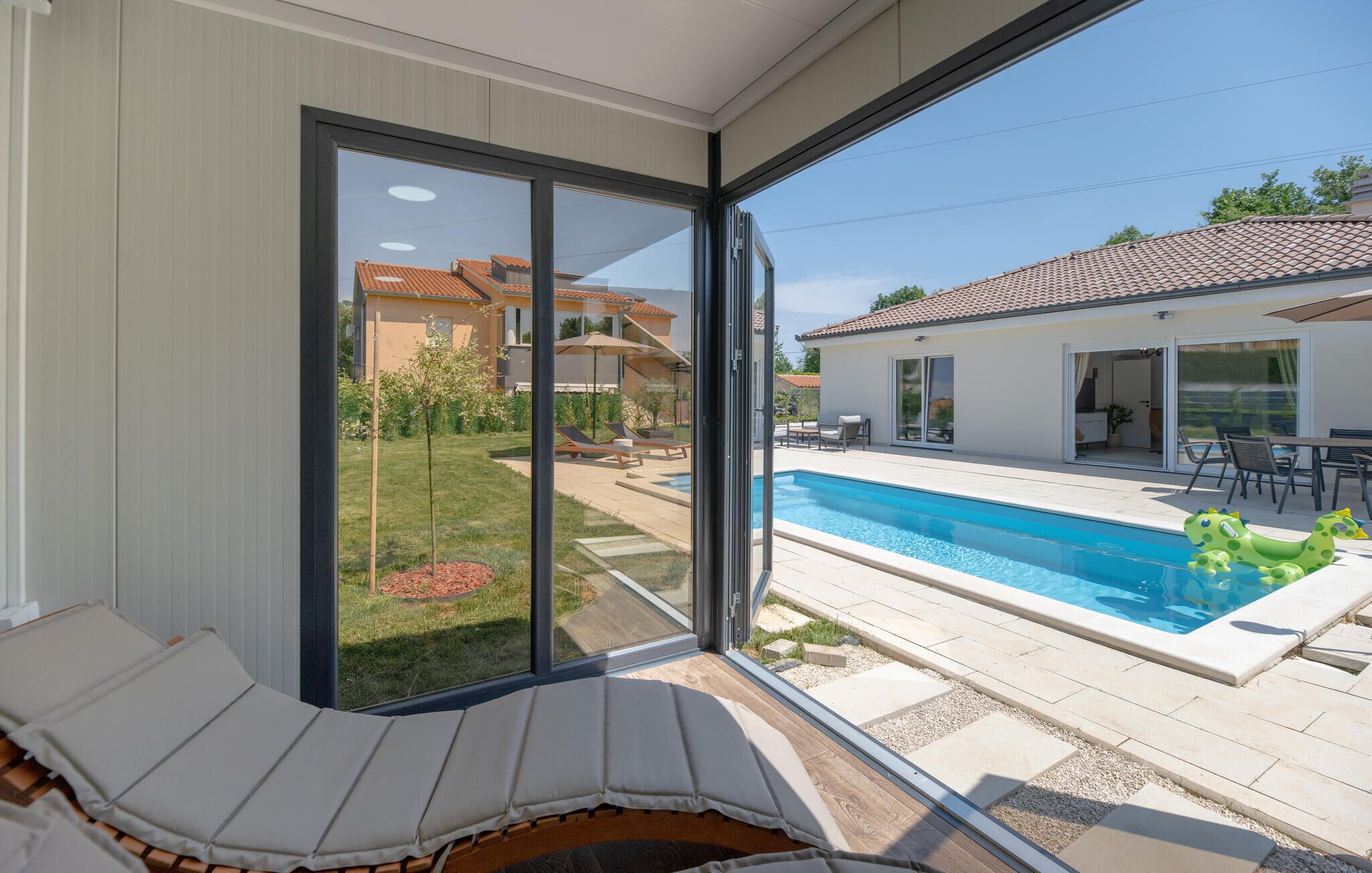 Un intérieur moderne avec une porte coulissante en verre donnant sur un espace piscine.