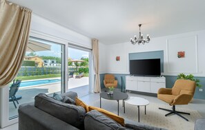 A modern living room with a sofa, armchairs, a TV, and a pool view. - Awesome home in Nedescina with sauna (Nedescina)
