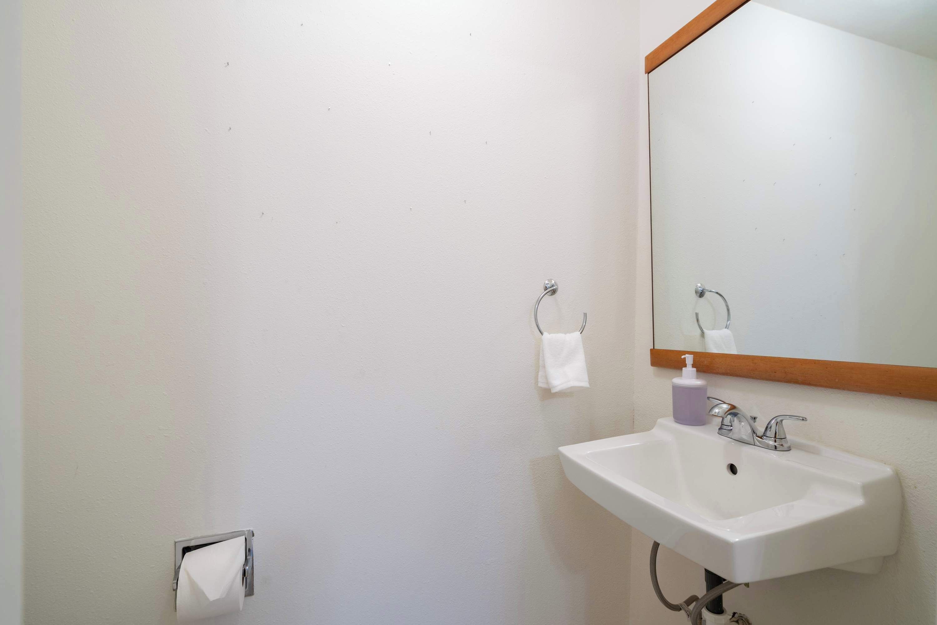 A bathroom with a white sink, a mirror, and a paper towel dispenser.