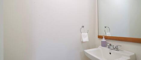 A bathroom with a white sink, a mirror, and a paper towel dispenser.