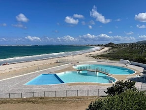 A beachside resort with a large swimming pool, a sandy beach, and a clear view of the ocean. - Sea view 1-bedroom LUXURY and cosy apartment in beautiful Orient Bay with AC (Saint Martin)