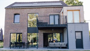A modern two-story house with a brick facade, large windows, and a balcony. - Le Surdan (Bassenge)