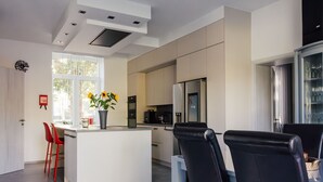 A modern kitchen with a central island, red chairs, and a dining table. - Le Surdan (Bassenge)