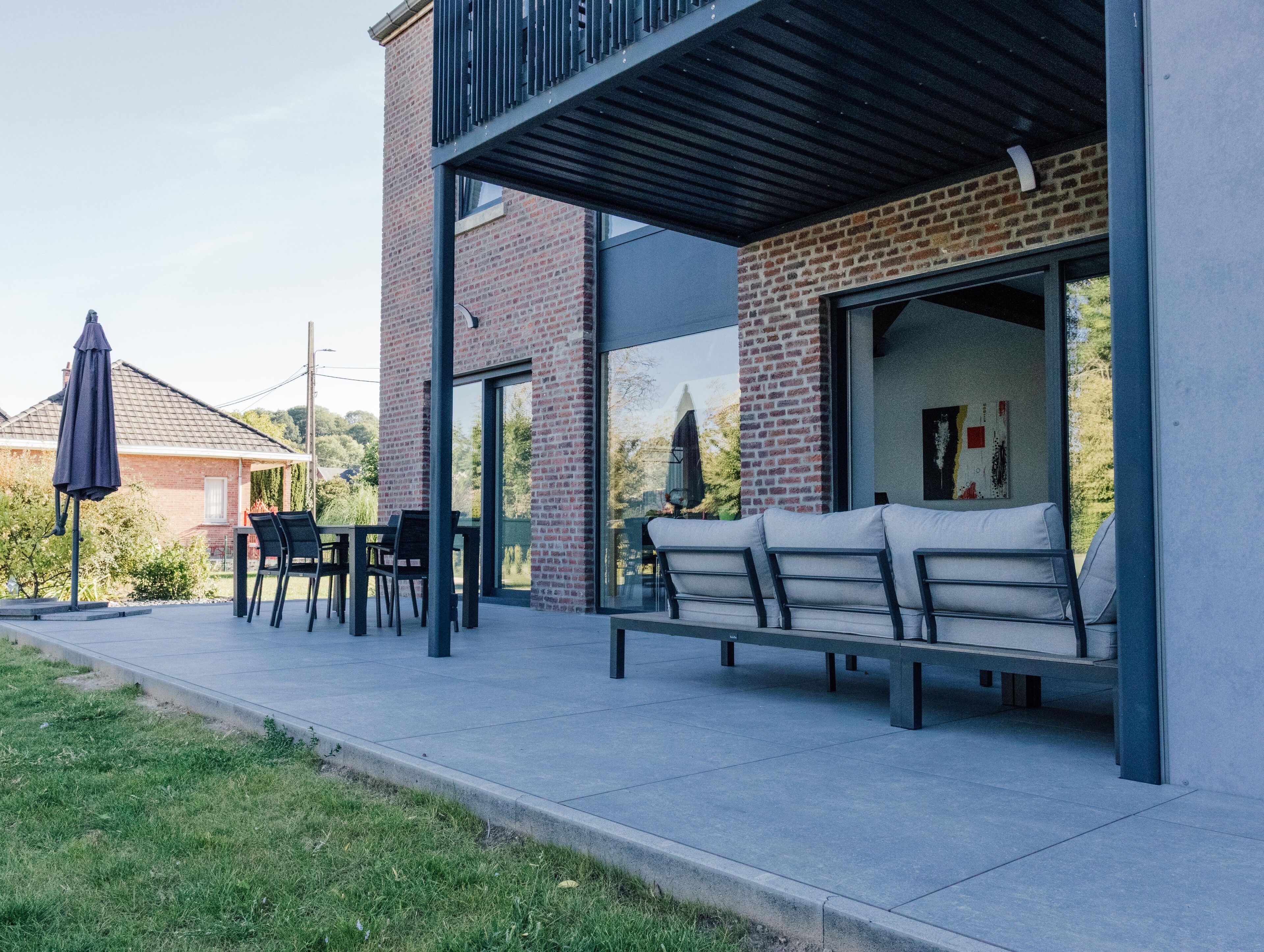 A modern outdoor seating area with a brick wall, a glass door, and a metal roof.