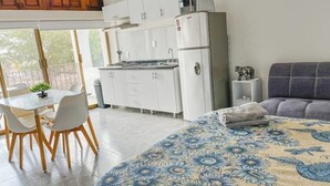 A compact living space with a kitchenette, a dining area, and a bed with a floral bedspread. - Beachfront Studio in PV (Puerto Vallarta)