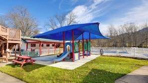 Un parque infantil con un tobogán, una mesa de picnic y una zona de juegos cubierta.