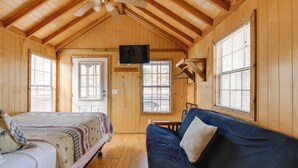 A wooden cabin with a bed, a sofa, a ceiling fan, and a TV mounted on the wall. - Escape to Blue Ridge Mtns! Studio w/ Resort Perks (Waynesville)