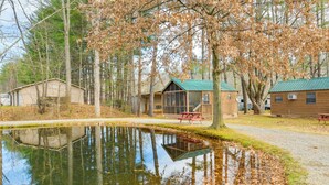 A cabin with a green roof, a pond reflecting trees, and a picnic table. - Escape to Blue Ridge Mtns! Studio w/ Resort Perks (Waynesville)