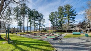 A playground with a climbing wall, swings, and a grassy area. - Cozy Couple’s Getaway Near Cataloochee Ski Area! (Waynesville)