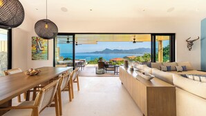 Un salon moderne doté d’une grande table à manger, de sièges confortables et offrant une vue sur la mer.