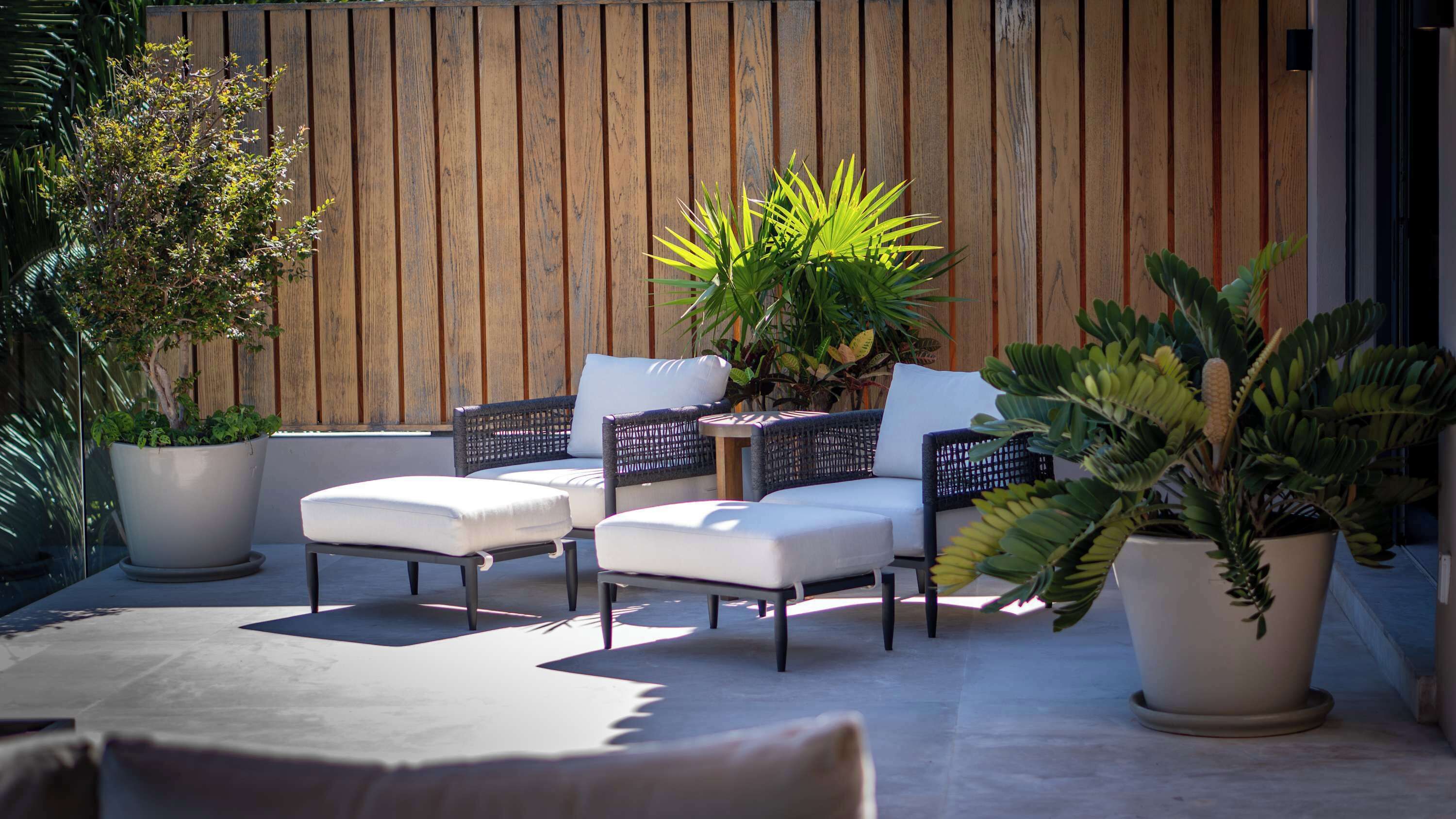 Eine Terrasse mit Gartenmöbeln, Blumentöpfen und einem Holzzaun.
