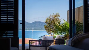 Une chambre avec vue sur la mer et les montagnes, comprenant un lit, une chaise et une plante.