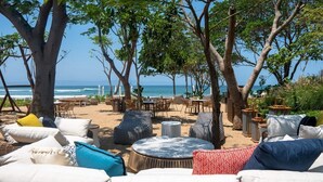 An outdoor seating area with round tables and chairs, surrounded by trees and overlooking the ocean. - Surfline Escape Luxury Ocean View + Golf Cart (Punta Mita)