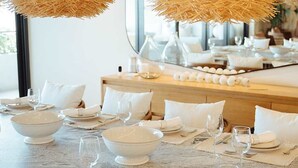 A dining area with a marble table set for a meal, featuring white bowls, plates, and cutlery. - Surfline Escape Luxury Ocean View + Golf Cart (Punta Mita)
