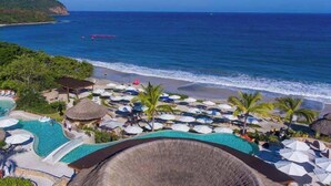 A resort with multiple swimming pools, beach umbrellas, and a view of the ocean. - Surfline Escape Luxury Ocean View + Golf Cart (Punta Mita)