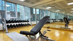 Une salle de sport équipée de matériel d’exercice, d’un banc et d’un porte-haltères.