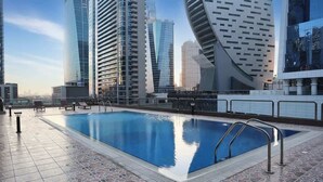 Une piscine sur le toit offrant une vue dégagée sur les immeubles modernes qui se dressent à l’horizon.