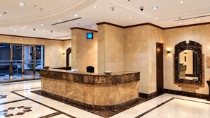 Un espace d’accueil doté d’un comptoir en marbre, d’un grand miroir et d’une porte en verre donnant sur l’extérieur.
