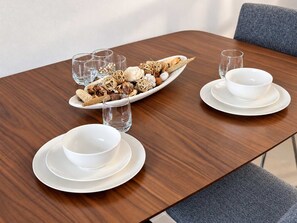 Une table à manger avec de l’assiette, des bols et des verres blancs, agrémentée d’un centre de table décoratif.