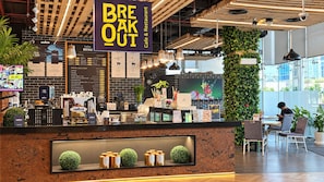 Un café au décor moderne, proposant une carte de boissons et de plats, et dont l’enseigne indique : « BREAK OUT Café et restaurant ».